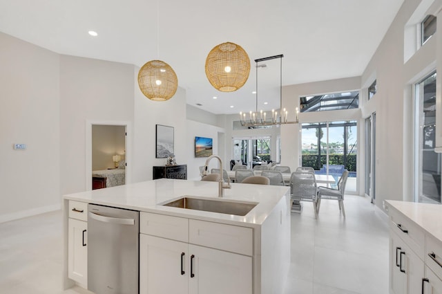 kitchen featuring open floor plan, light countertops, stainless steel dishwasher, pendant lighting, and a sink