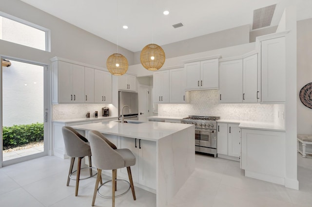 kitchen featuring visible vents, light countertops, a sink, and high end range