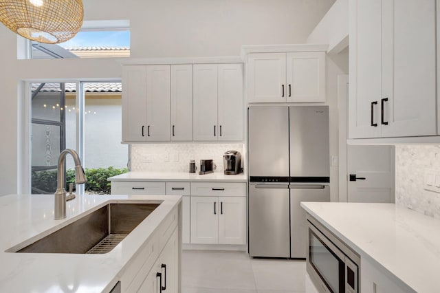 kitchen featuring appliances with stainless steel finishes, backsplash, a sink, and white cabinets