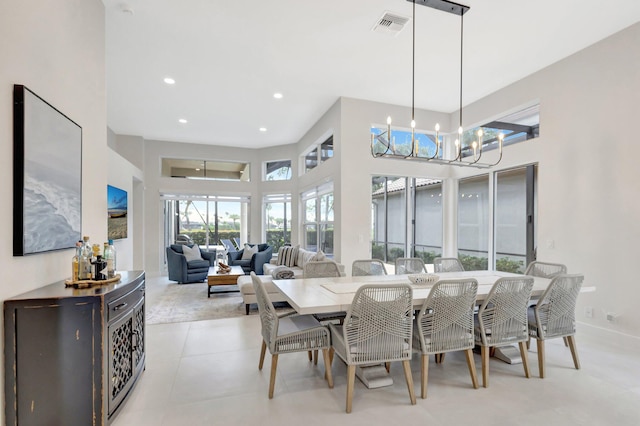 dining room featuring baseboards, visible vents, a towering ceiling, a chandelier, and recessed lighting