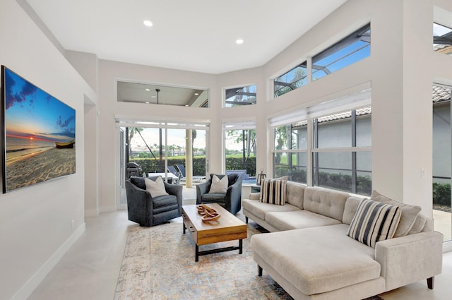 living area featuring a wealth of natural light, a towering ceiling, baseboards, and recessed lighting