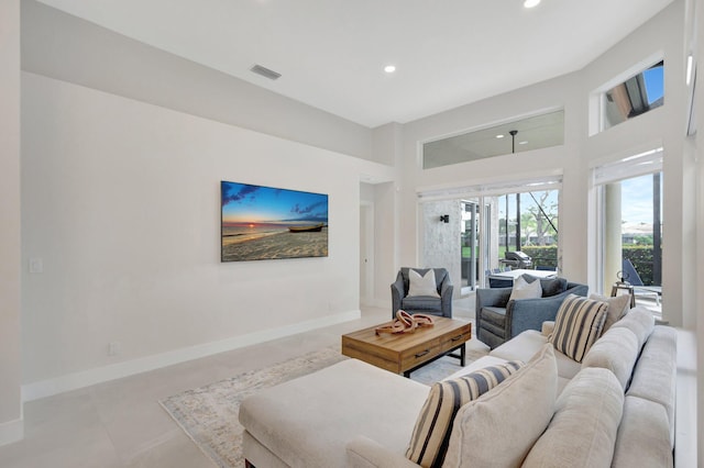 living area with baseboards, a high ceiling, visible vents, and recessed lighting