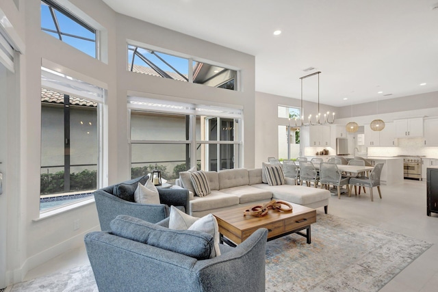 living area featuring a wealth of natural light, baseboards, a notable chandelier, and recessed lighting