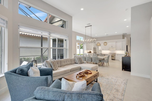 living area featuring a towering ceiling, baseboards, a chandelier, and recessed lighting