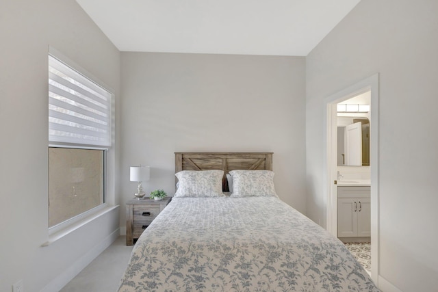 bedroom with ensuite bathroom, a sink, and baseboards