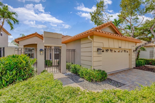 mediterranean / spanish house featuring a garage, a gate, fence, and a tiled roof