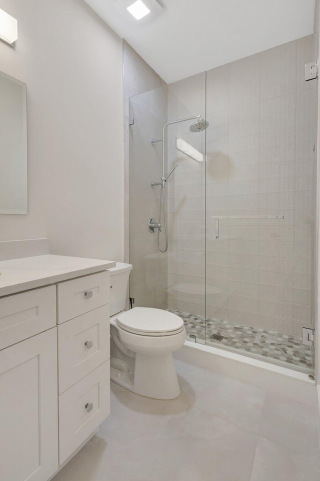 bathroom with toilet, a shower stall, vanity, and tile patterned floors