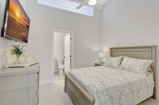 bedroom featuring ensuite bathroom, ceiling fan, a towering ceiling, and baseboards