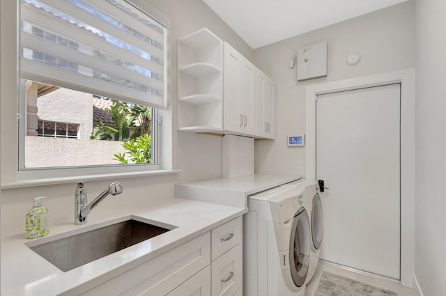 washroom featuring independent washer and dryer, a sink, and cabinet space