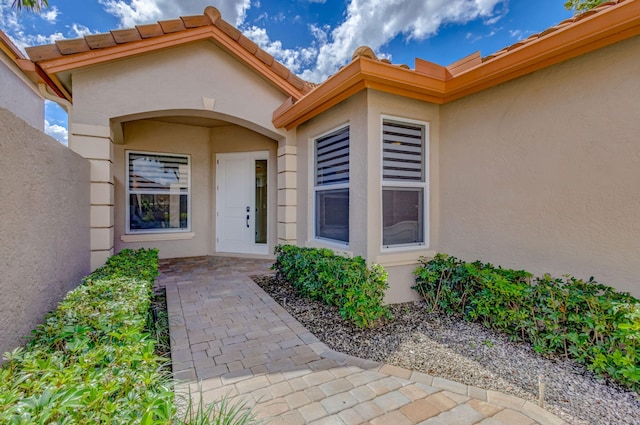 entrance to property with a tile roof and stucco siding