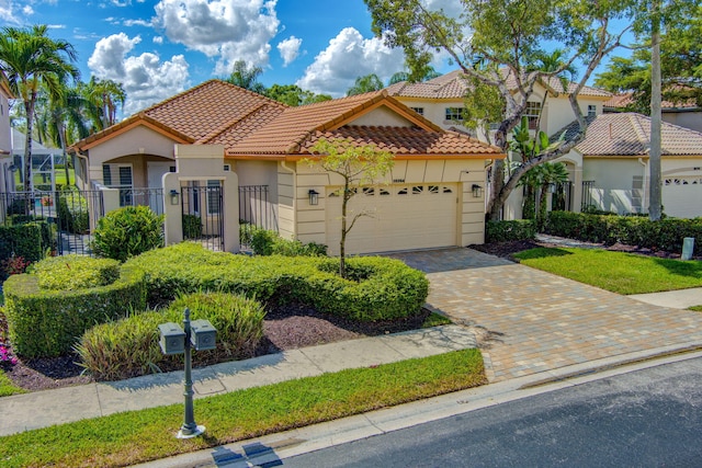 mediterranean / spanish-style home featuring a garage, a tile roof, fence, decorative driveway, and stucco siding