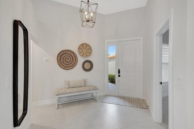 entrance foyer featuring a towering ceiling, baseboards, and a chandelier