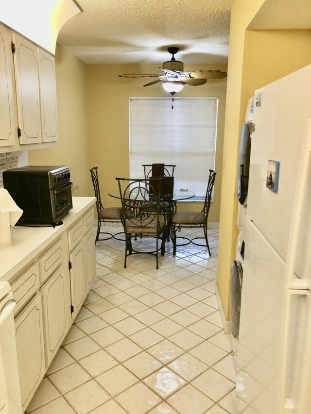 kitchen featuring a toaster, light countertops, freestanding refrigerator, ceiling fan, and a textured ceiling