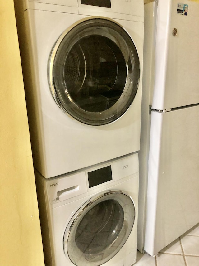 washroom featuring stacked washing maching and dryer, laundry area, and light tile patterned flooring