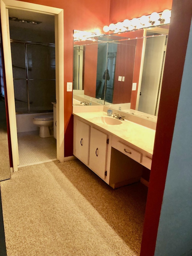 full bath with enclosed tub / shower combo, vanity, and toilet