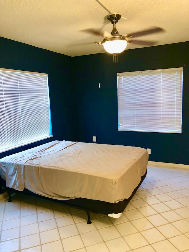 bedroom with light tile patterned floors, ceiling fan, and a textured ceiling