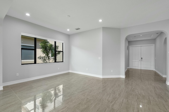 unfurnished room featuring arched walkways, recessed lighting, visible vents, and baseboards