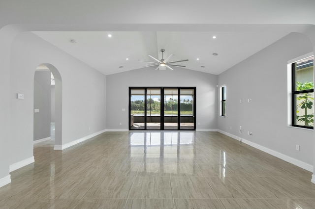 empty room featuring plenty of natural light, arched walkways, and baseboards