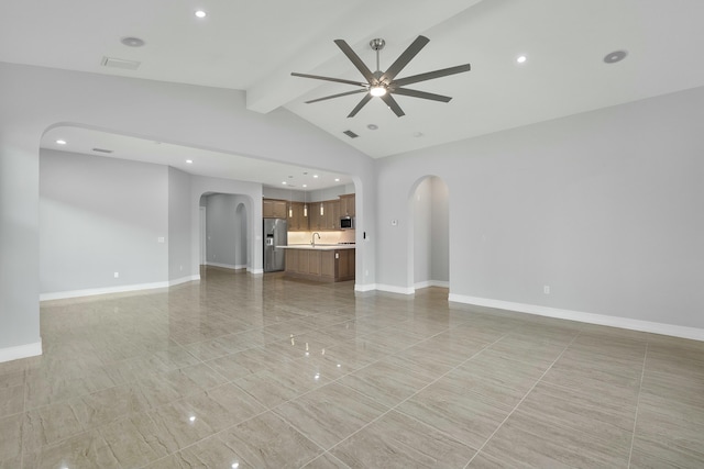 unfurnished living room featuring baseboards, arched walkways, a ceiling fan, vaulted ceiling with beams, and a sink