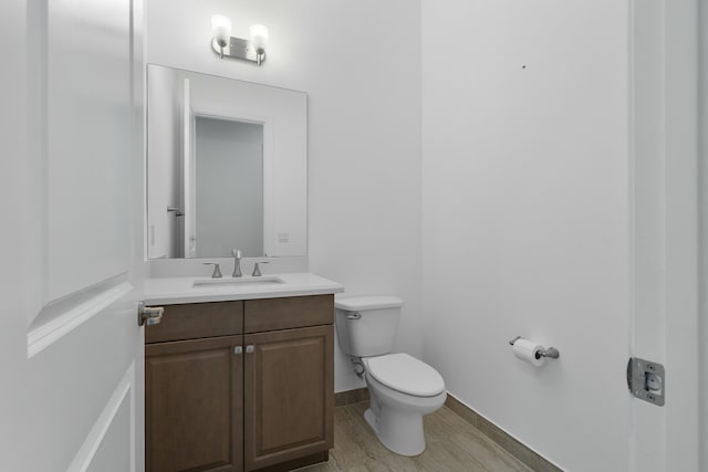 half bath featuring wood finished floors, vanity, toilet, and baseboards