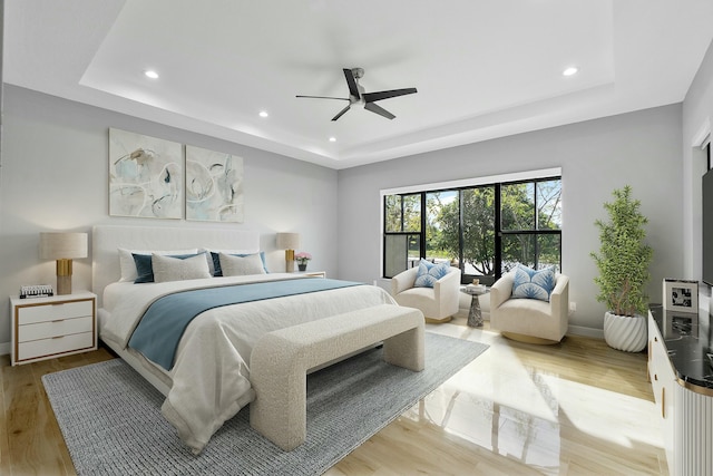 bedroom featuring baseboards, a tray ceiling, wood finished floors, and recessed lighting