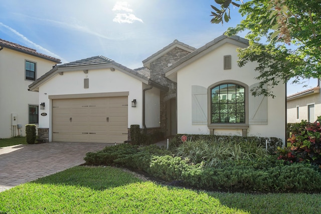 view of front of home with an attached garage, stone siding, a tiled roof, decorative driveway, and stucco siding