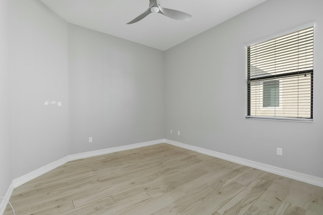 spare room featuring a ceiling fan, light wood-type flooring, and baseboards