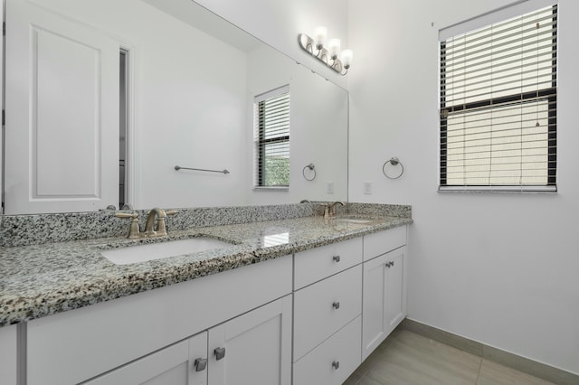 full bathroom featuring double vanity, a sink, and baseboards