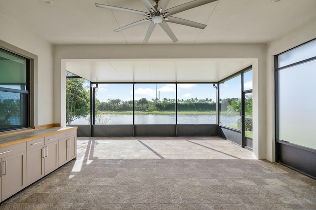 unfurnished sunroom featuring a water view and a ceiling fan