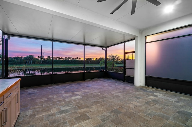 unfurnished sunroom with a water view and ceiling fan