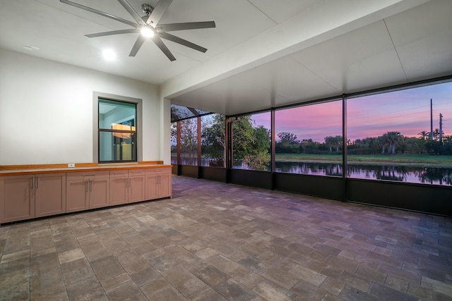 unfurnished sunroom featuring a water view and a ceiling fan