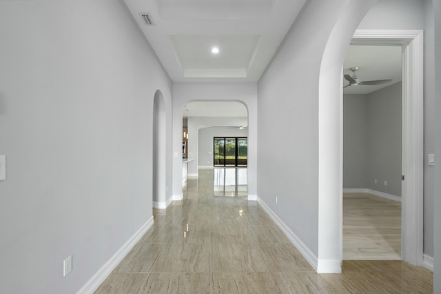 hall with arched walkways, visible vents, and baseboards