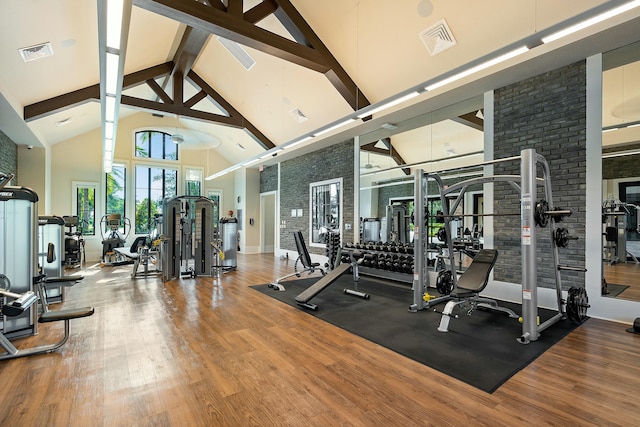 exercise room featuring high vaulted ceiling, visible vents, and wood finished floors