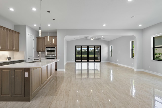 kitchen with arched walkways, light countertops, stainless steel double oven, open floor plan, and a large island with sink