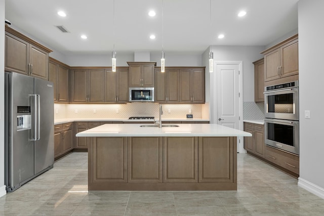 kitchen with stainless steel appliances, light countertops, visible vents, a kitchen island with sink, and a sink