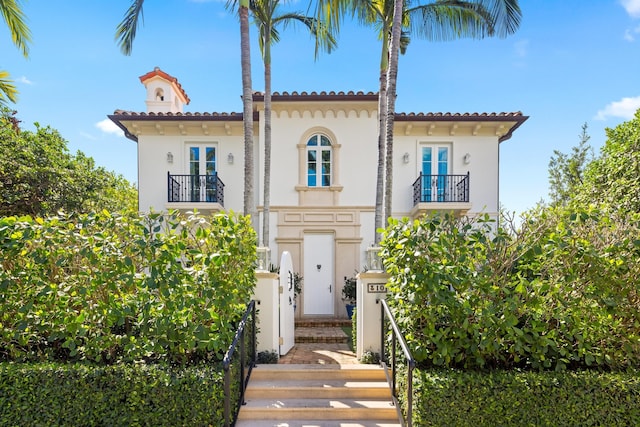 mediterranean / spanish home with a balcony, a tile roof, and stucco siding