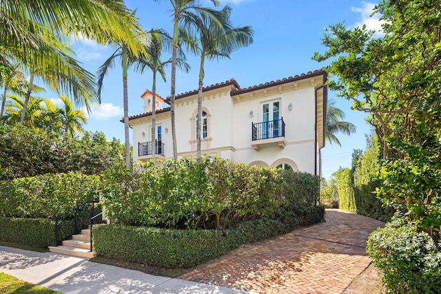 mediterranean / spanish home with a balcony, a tiled roof, and stucco siding