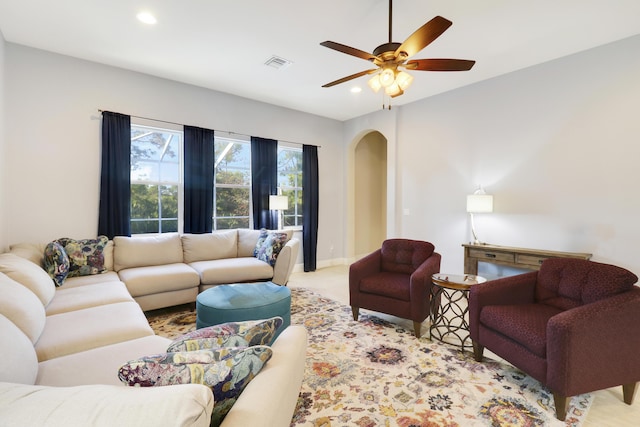 living area with arched walkways, recessed lighting, light colored carpet, visible vents, and ceiling fan