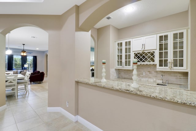 interior space featuring arched walkways, light tile patterned flooring, visible vents, and decorative backsplash