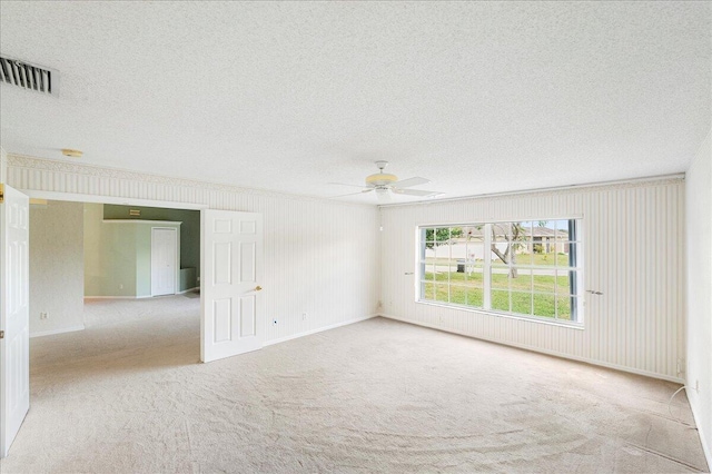 carpeted empty room with baseboards, ceiling fan, visible vents, and a textured ceiling