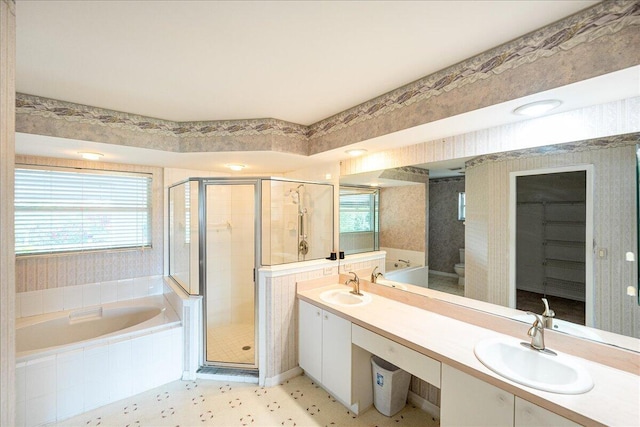 bathroom with a garden tub, a sink, a shower stall, and wallpapered walls