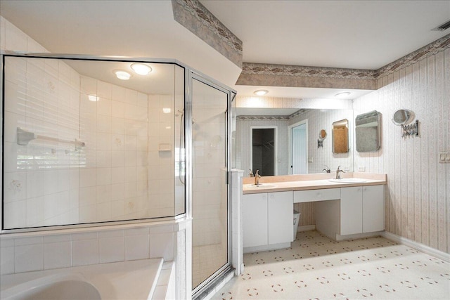 full bath featuring double vanity, wallpapered walls, a stall shower, a garden tub, and a sink