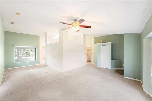 empty room with lofted ceiling, visible vents, light colored carpet, and a textured ceiling