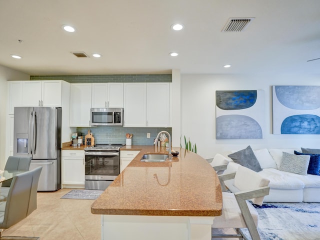 kitchen featuring appliances with stainless steel finishes, visible vents, a sink, and a peninsula