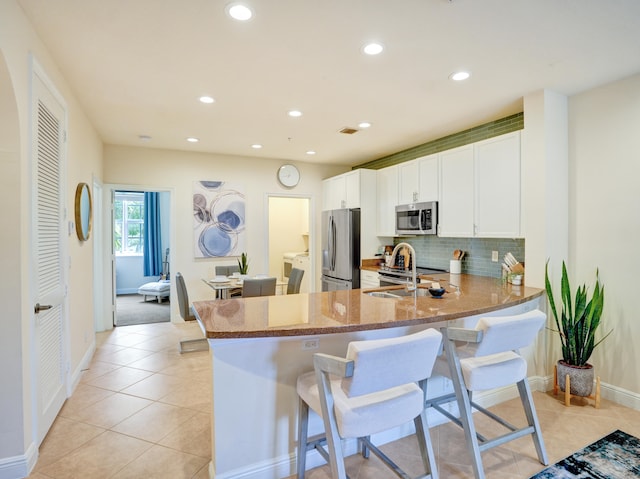 kitchen with stone counters, a breakfast bar, light tile patterned floors, tasteful backsplash, and appliances with stainless steel finishes