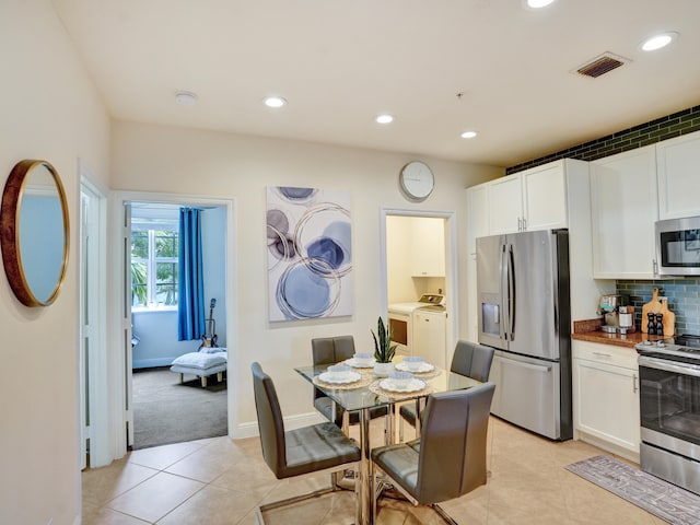 dining area featuring light tile patterned flooring, washing machine and dryer, visible vents, and recessed lighting