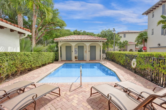 pool with an outbuilding, a patio area, and fence