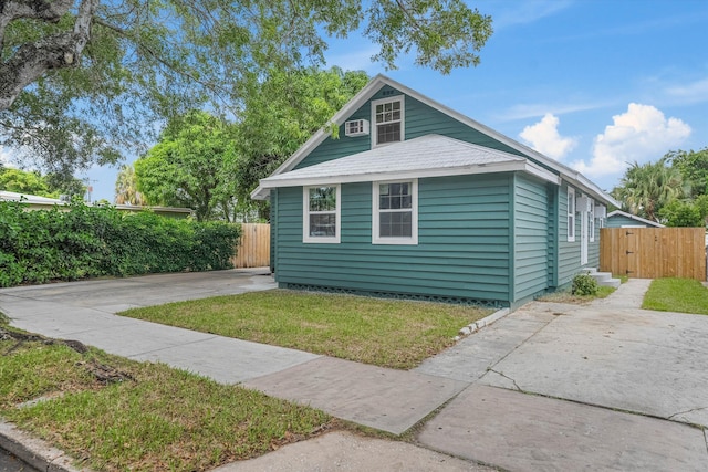 view of side of home featuring concrete driveway and fence