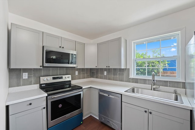 kitchen with appliances with stainless steel finishes, gray cabinets, and a sink