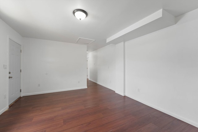 spare room with attic access, baseboards, and wood finished floors